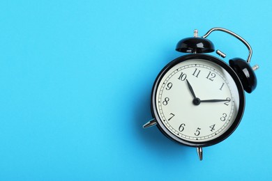 Photo of Alarm clock on light blue background, top view with space for text. School time