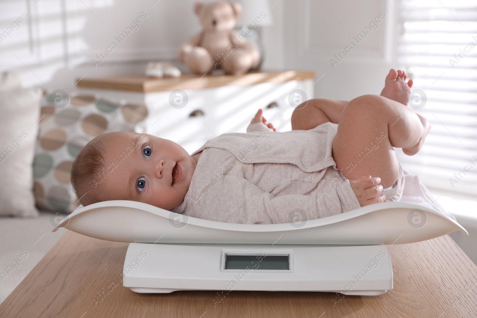 Photo of Cute little baby lying on scales at home