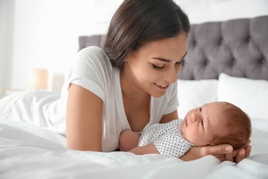 Photo of Young woman with her newborn baby on bed