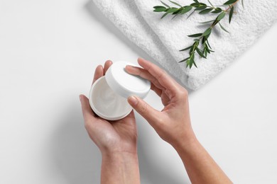 Photo of Woman with jar of hand cream, towel and green twigs on white background, top view