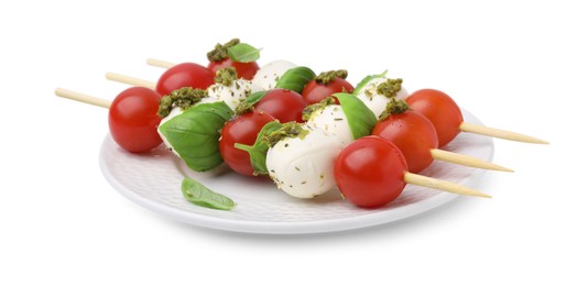 Photo of Plate of Caprese skewers with tomatoes, mozzarella balls, basil and pesto sauce isolated on white