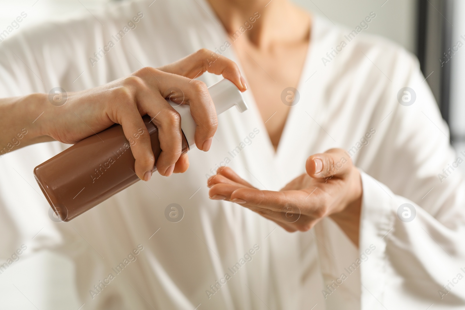 Photo of Woman applying self-tanning product onto hand, closeup