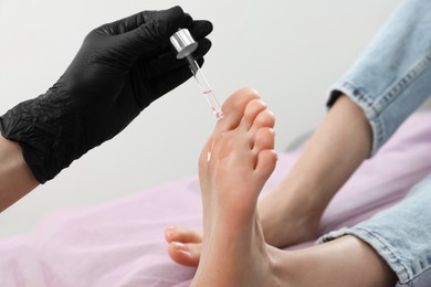 Professional master pouring oil on client's foot in beauty salon, closeup. Pedicure procedure