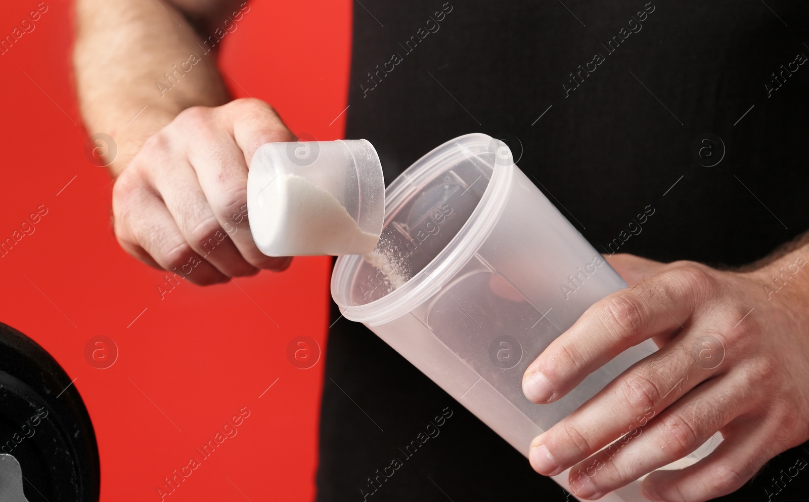 Photo of Man preparing protein shake against red background, closeup