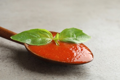 Photo of Spoon of tomato sauce on grey table, closeup. Space for text