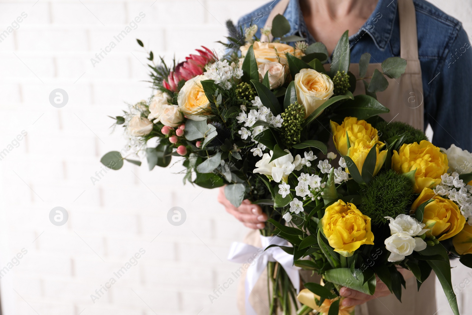 Photo of Woman with beautiful bouquets near white brick wall, closeup