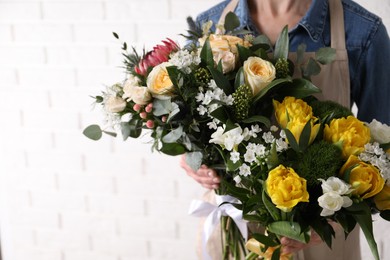 Woman with beautiful bouquets near white brick wall, closeup