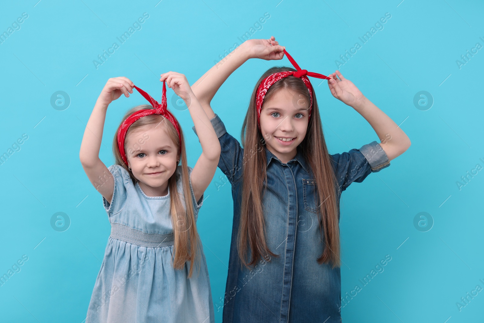 Photo of Cute little sisters on light blue background