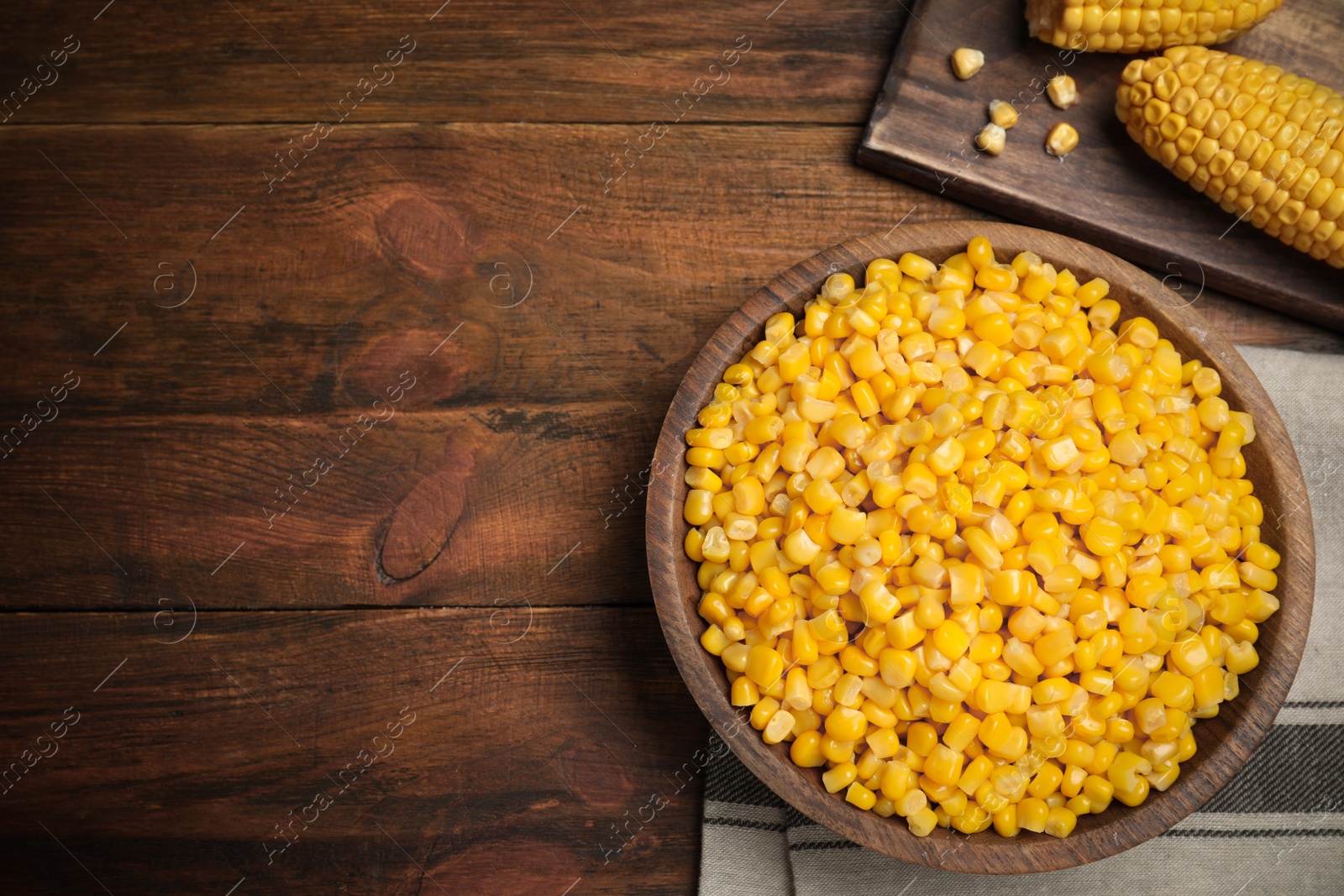 Photo of Delicious canned corn in bowl on wooden table, flat lay. Space for text