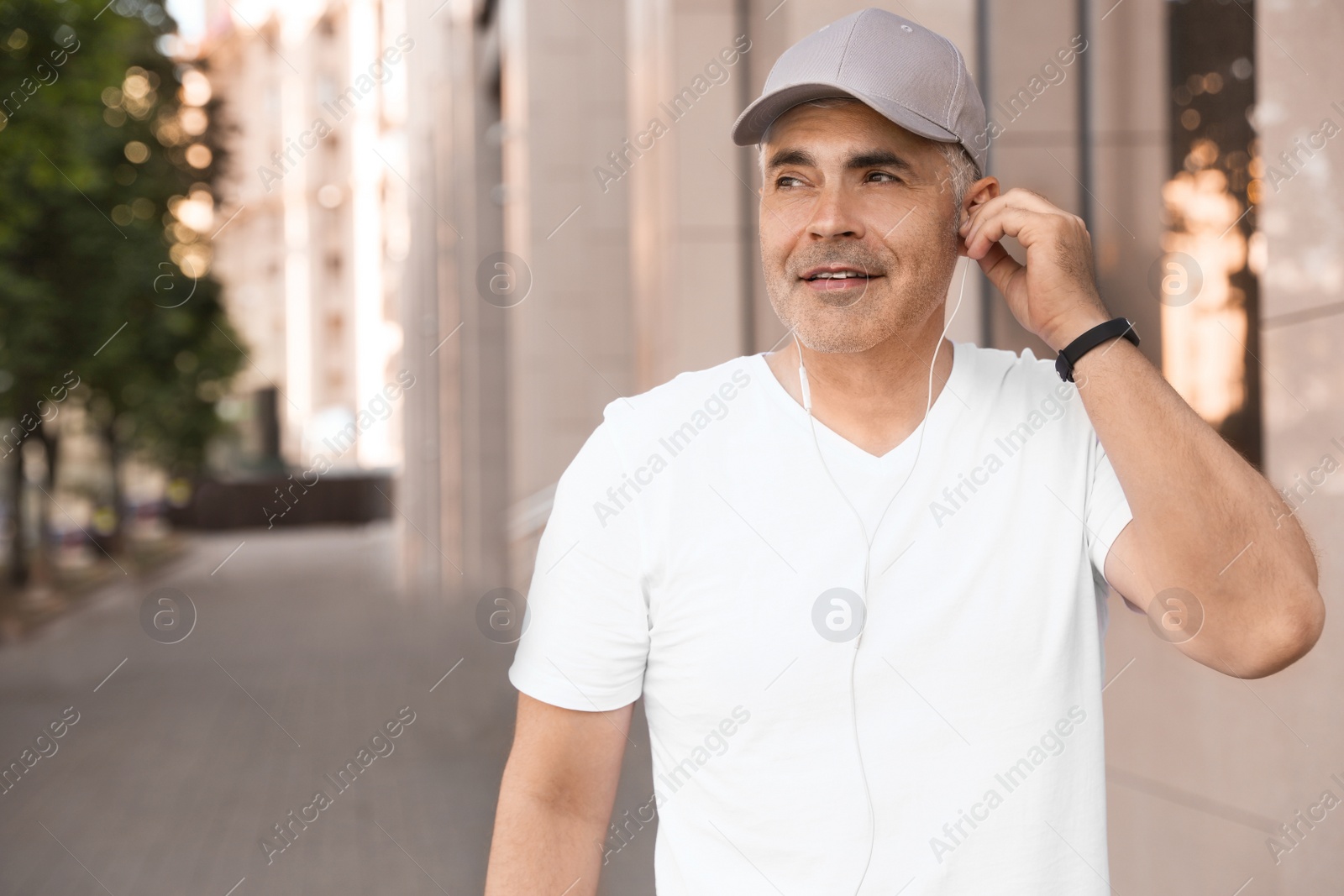 Photo of Handsome mature man listening to music on street, space for text. Healthy lifestyle