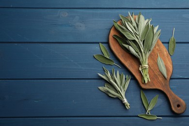 Board with fresh green sage on blue wooden table, flat lay. Space for text