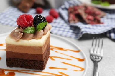 Piece of triple chocolate mousse cake with fresh berries on light grey table, closeup. Space for text