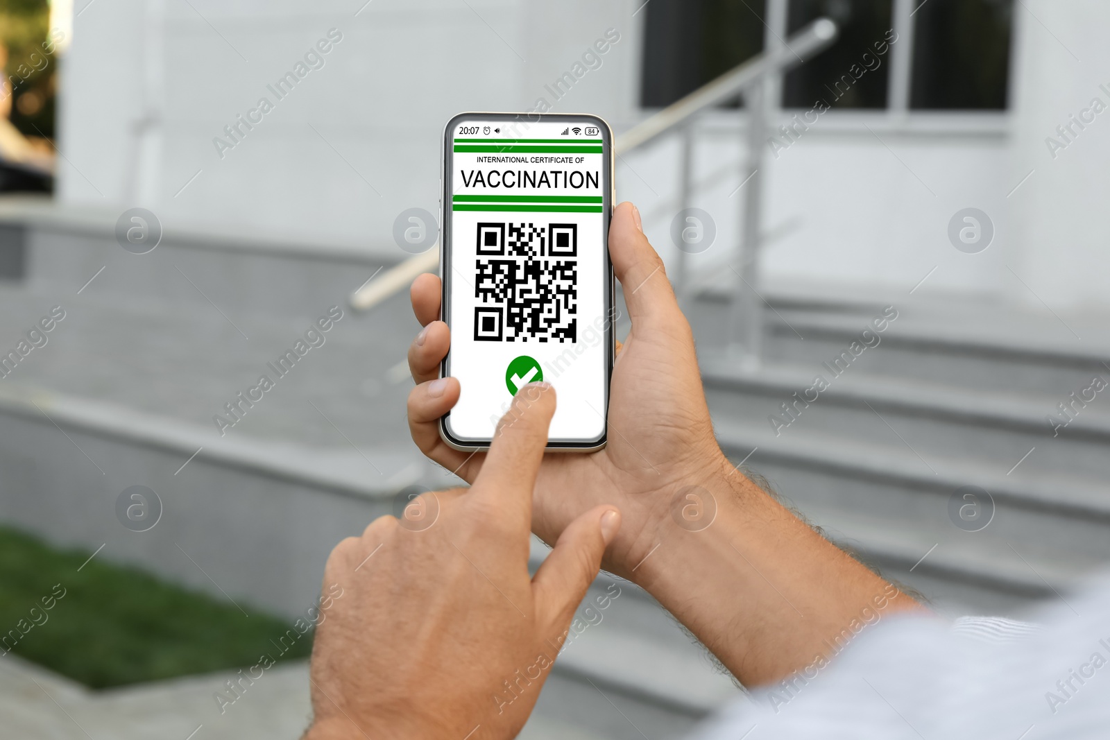 Image of Man holding smartphone with international certificate of vaccination outdoors, closeup