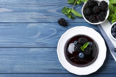 Delicious fresh jelly with berries on blue wooden table, flat lay. Space for text