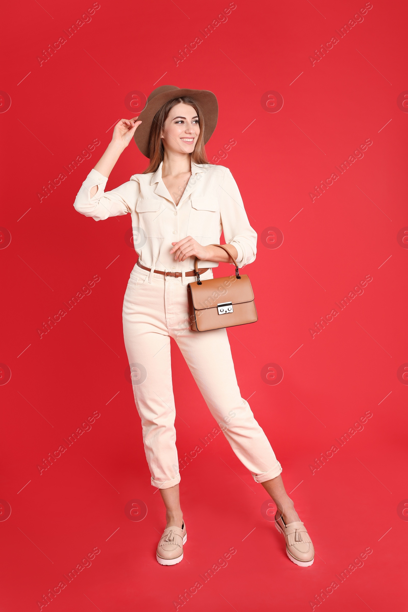 Photo of Beautiful young woman in casual outfit with stylish bag on red background