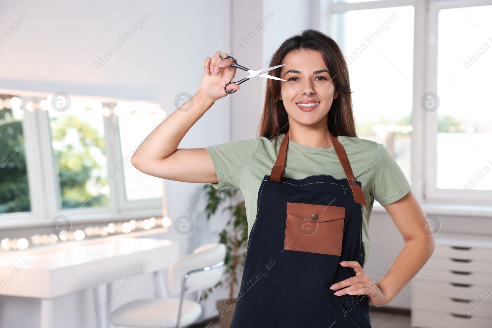 Photo of Portrait of happy hairdresser with professional scissors in beauty salon