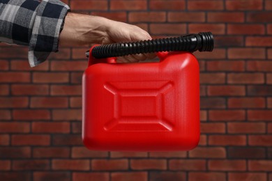 Photo of Man holding red canister against brick wall, closeup