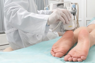 Photo of Doctor conducting ultrasound examination of patient's foot in clinic, closeup