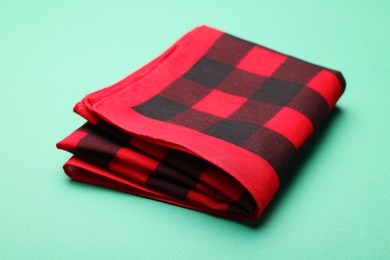 Photo of Folded red checkered bandana on turquoise background