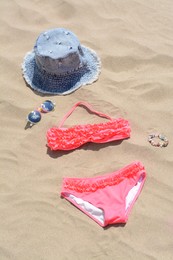 Photo of Jeans hat, sunglasses and bikini on sand. Beach accessories