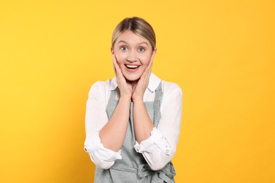 Photo of Beautiful young woman in clean apron with pattern on orange background