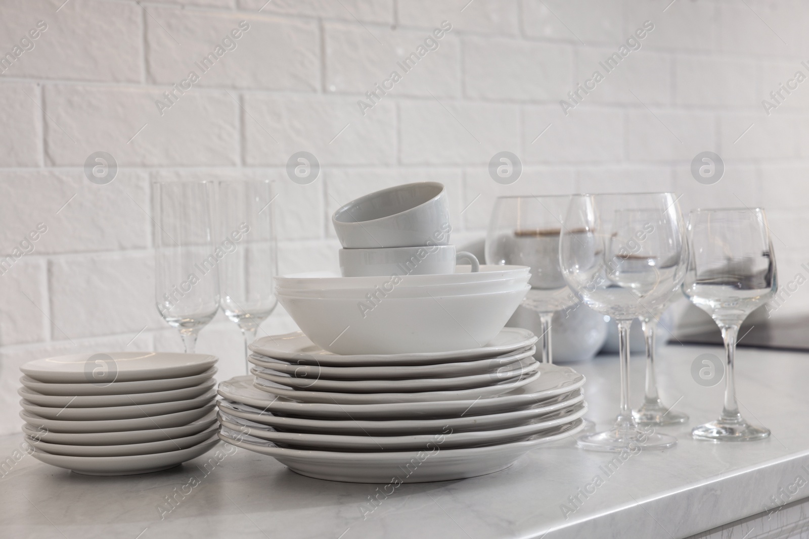 Photo of Different clean dishware, cups and glasses on countertop in kitchen