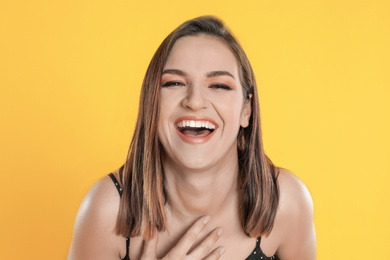 Happy beautiful young woman on yellow background