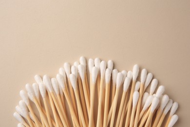 Many clean cotton buds on beige background, flat lay. Space for text