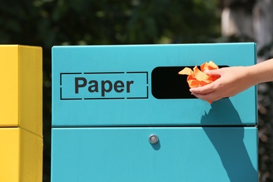 Photo of Woman throwing crumpled paper into sorting bin on city street, closeup. Recycling waste