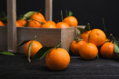 Fresh ripe tangerines with green leaves and wooden basket on table