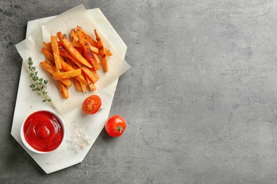 Photo of Board with sweet potato fries on grey background, top view. Space for text