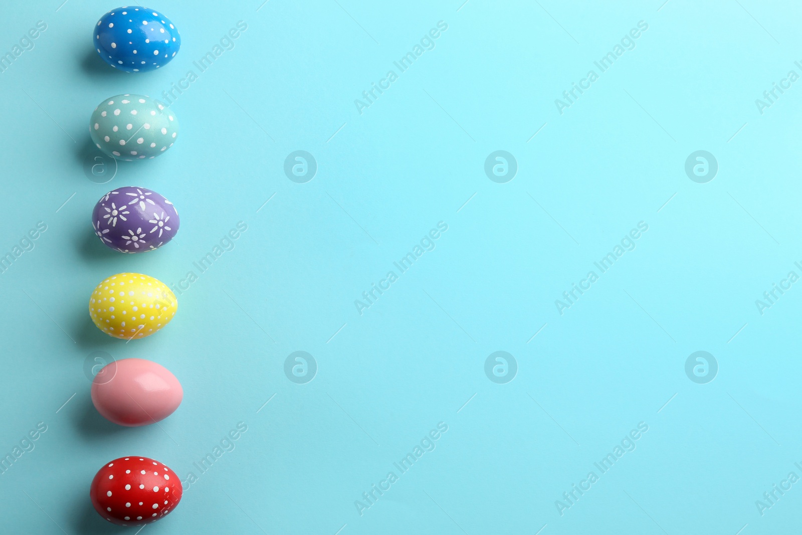 Photo of Flat lay composition of painted Easter eggs on color background, space for text