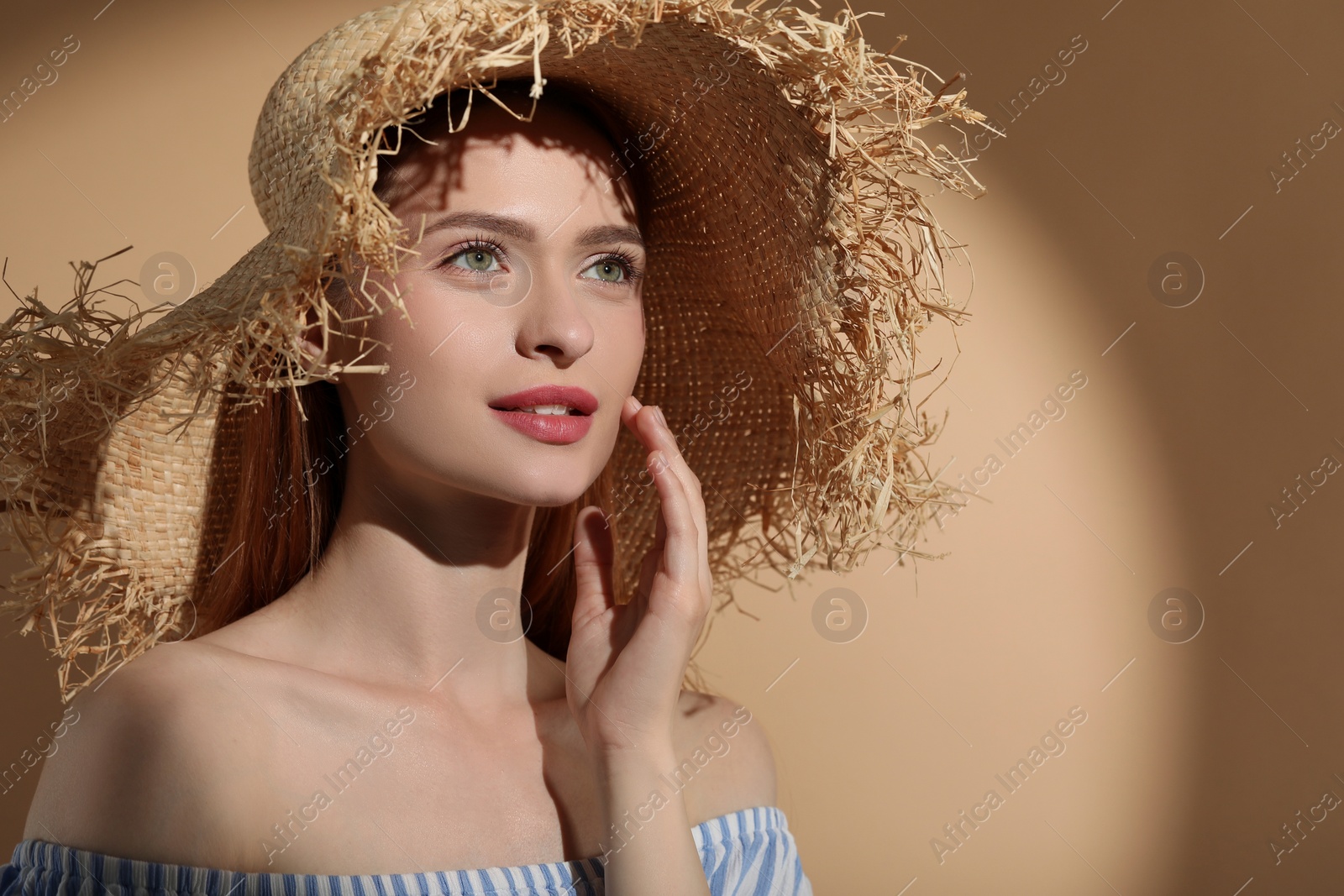 Photo of Beautiful young woman in sunlight on beige background, space for text