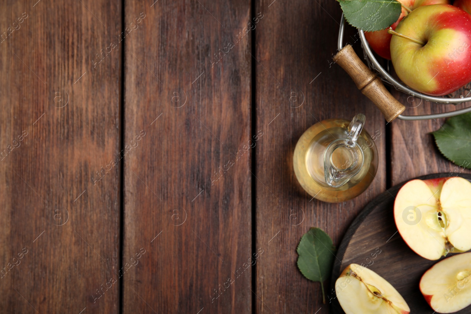 Photo of Natural apple vinegar and fresh fruits on wooden table, flat lay. Space for text