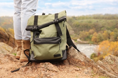 Photo of Woman wearing stylish hiking boots with backpack on steep cliff, closeup