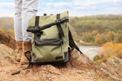 Woman wearing stylish hiking boots with backpack on steep cliff, closeup