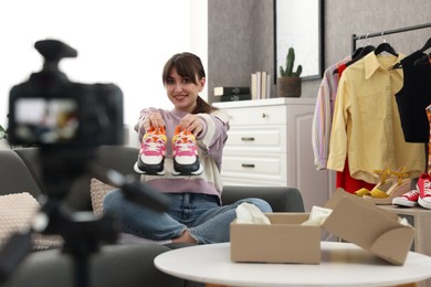 Photo of Smiling fashion blogger showing her shoes while recording video at home