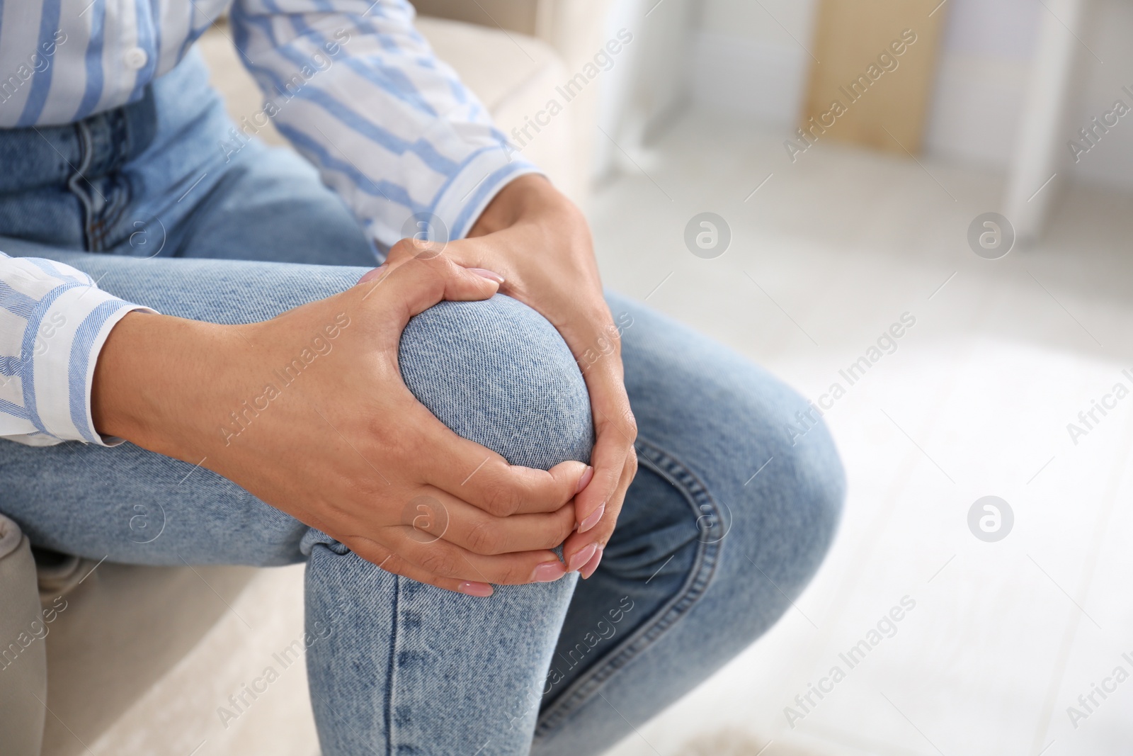 Photo of Woman suffering from knee pain at home, closeup. Health problems