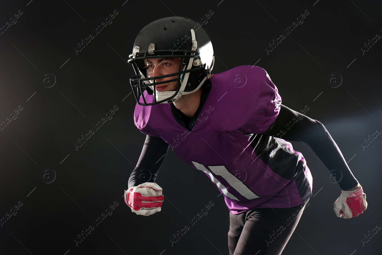 Photo of American football player wearing uniform on dark background