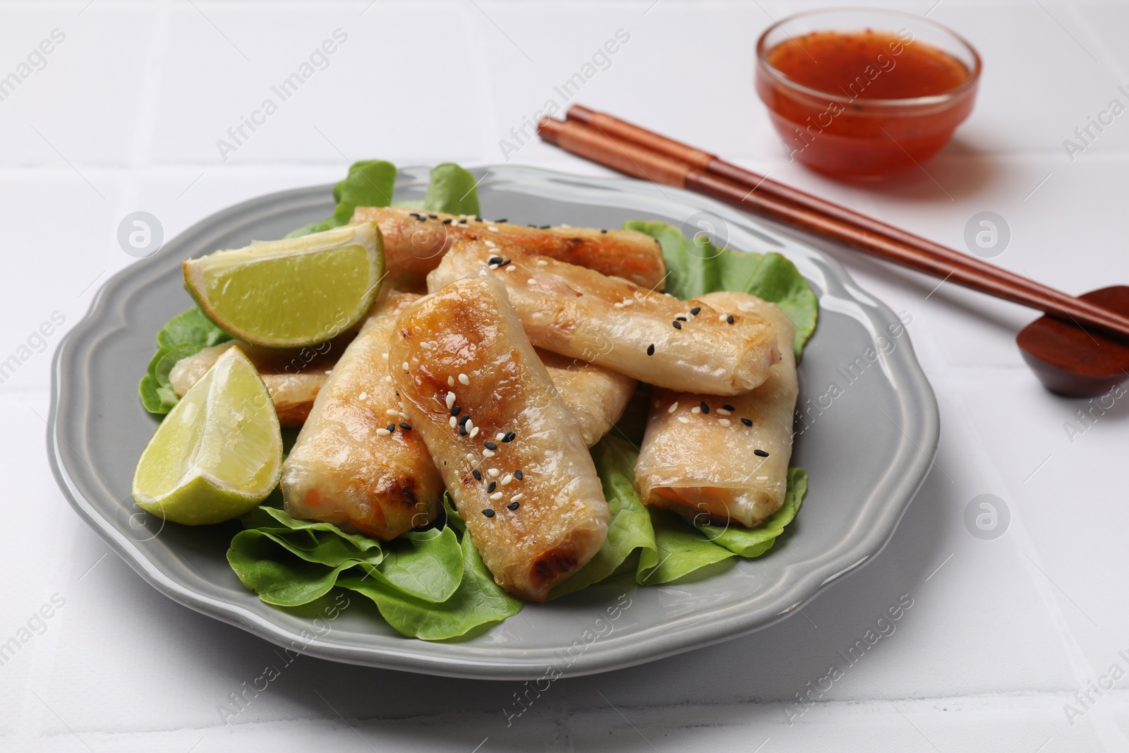 Photo of Tasty fried spring rolls served on white table, closeup