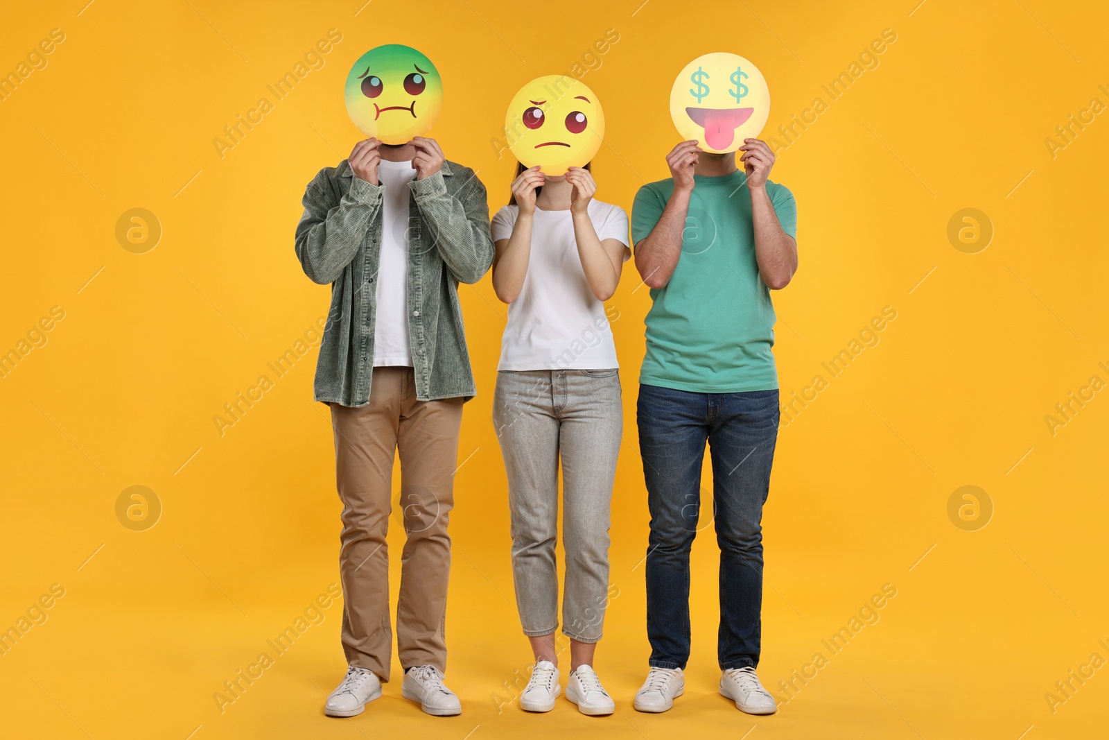 Photo of People covering faces with emoticons on yellow background