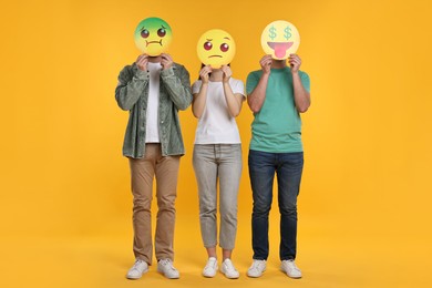 Photo of People covering faces with emoticons on yellow background