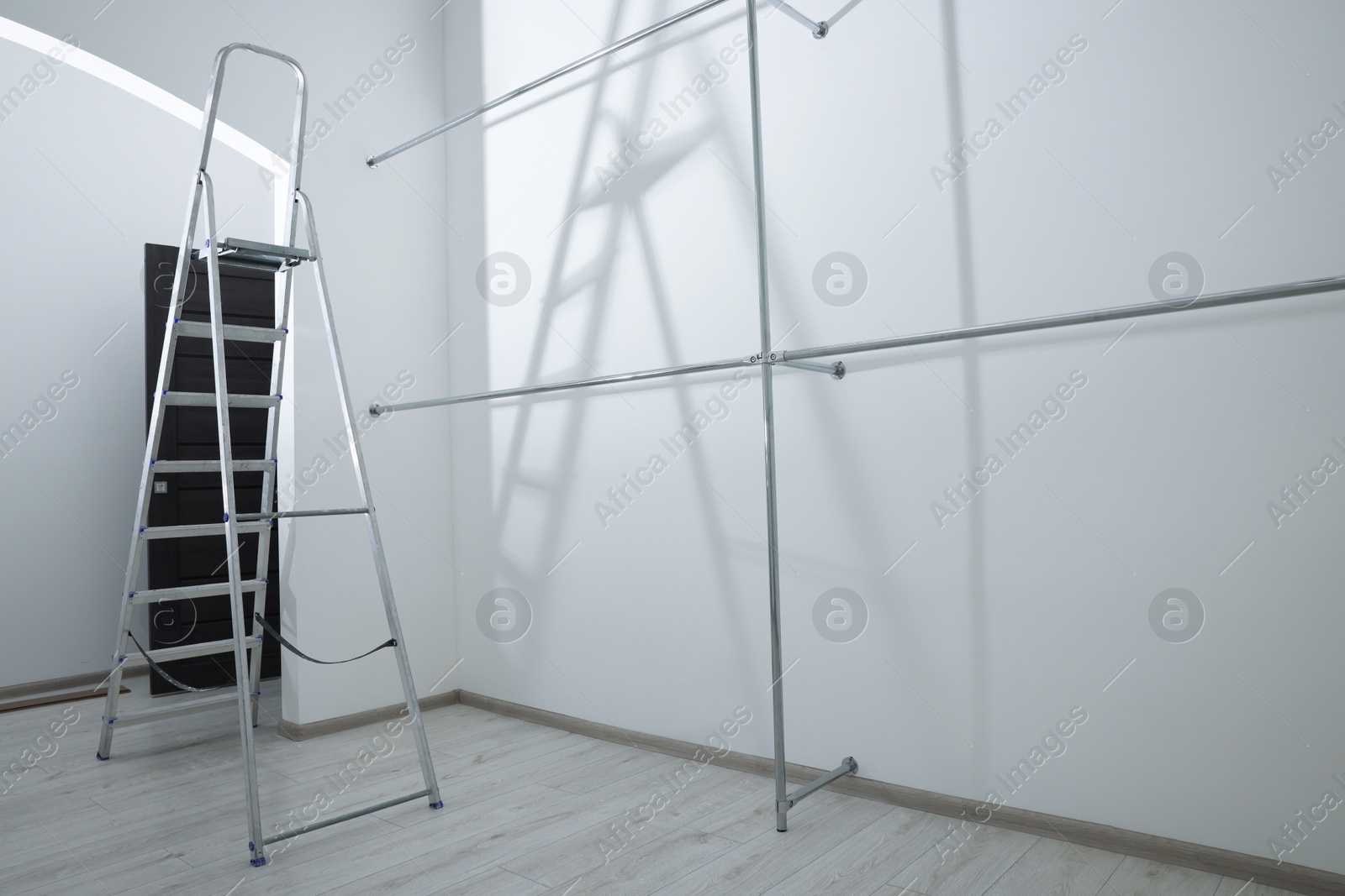 Photo of Ladder and metal pipes in empty renovated room