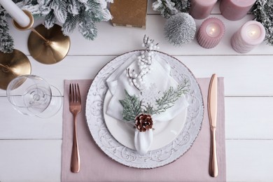 Festive place setting with beautiful dishware, cutlery and cone for Christmas dinner on white wooden table, flat lay