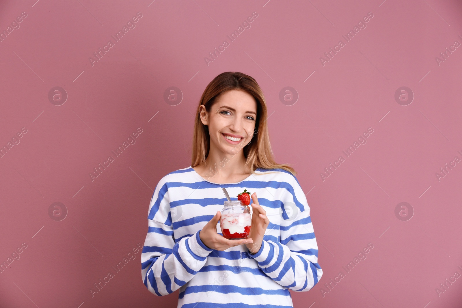 Photo of Young attractive woman eating tasty yogurt on color background