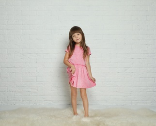 Portrait of cute little girl against brick wall