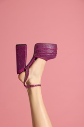 Photo of Woman wearing high heeled shoe with platform and square toes on pink background, closeup