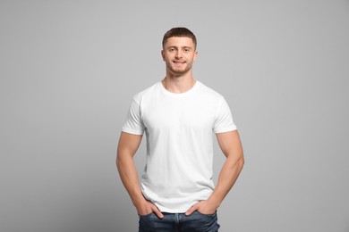 Man wearing white t-shirt on light grey background. Mockup for design