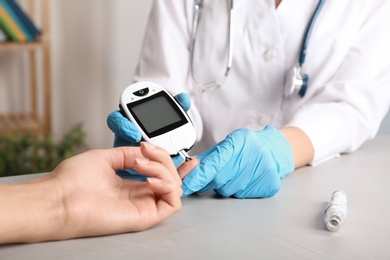 Photo of Doctor checking blood sugar level with glucometer at table. Diabetes test