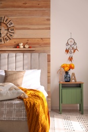 Photo of Beautiful dream catcher hanging near bed in stylish room interior